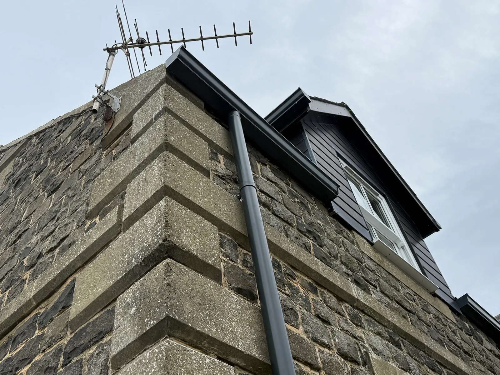 Anthracite guttering, fascia and downpipe on a stone-built property in Alnwick, below a clad dormer.
