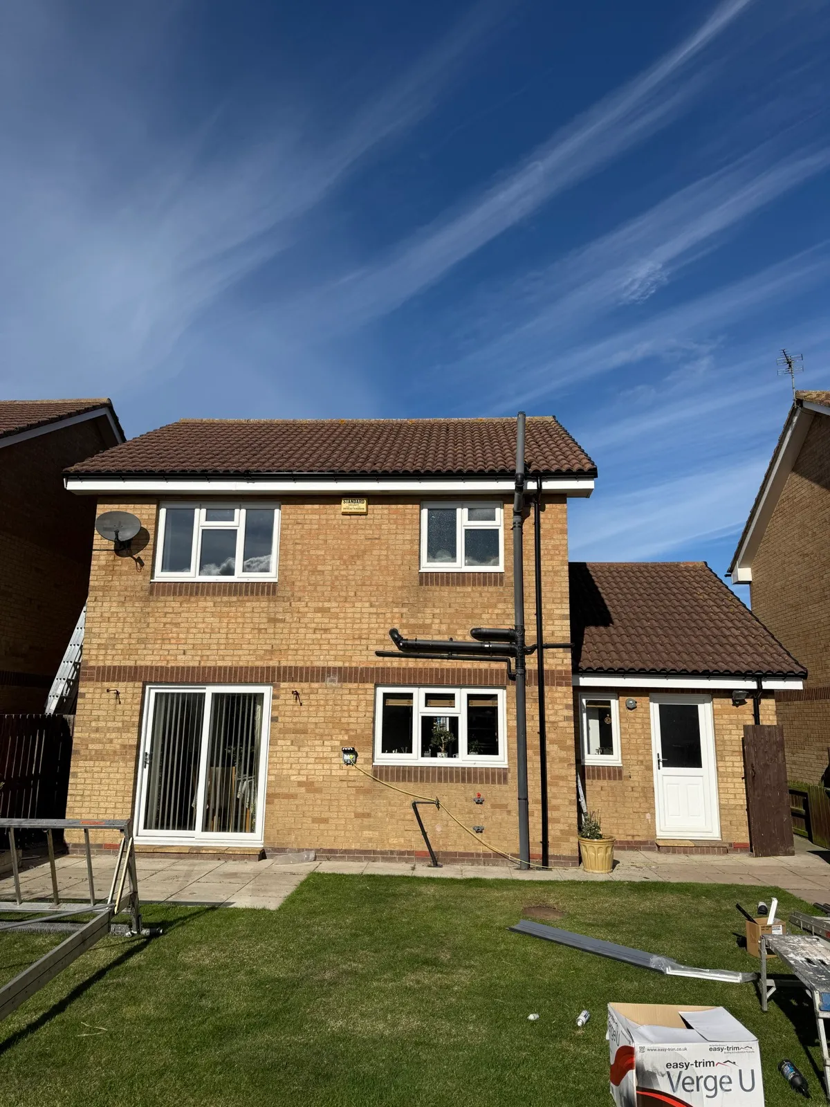 Rear elevation of the Amble property showing white roofline and black guttering, with installation materials still on site.
