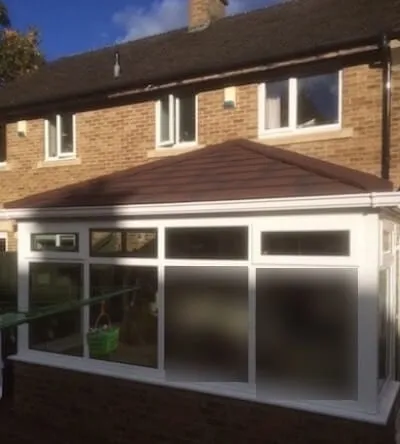 A white conservatory with a tiled roof along the back of a two-storey brick house in Great Lumley, with a washing line in front of it.
