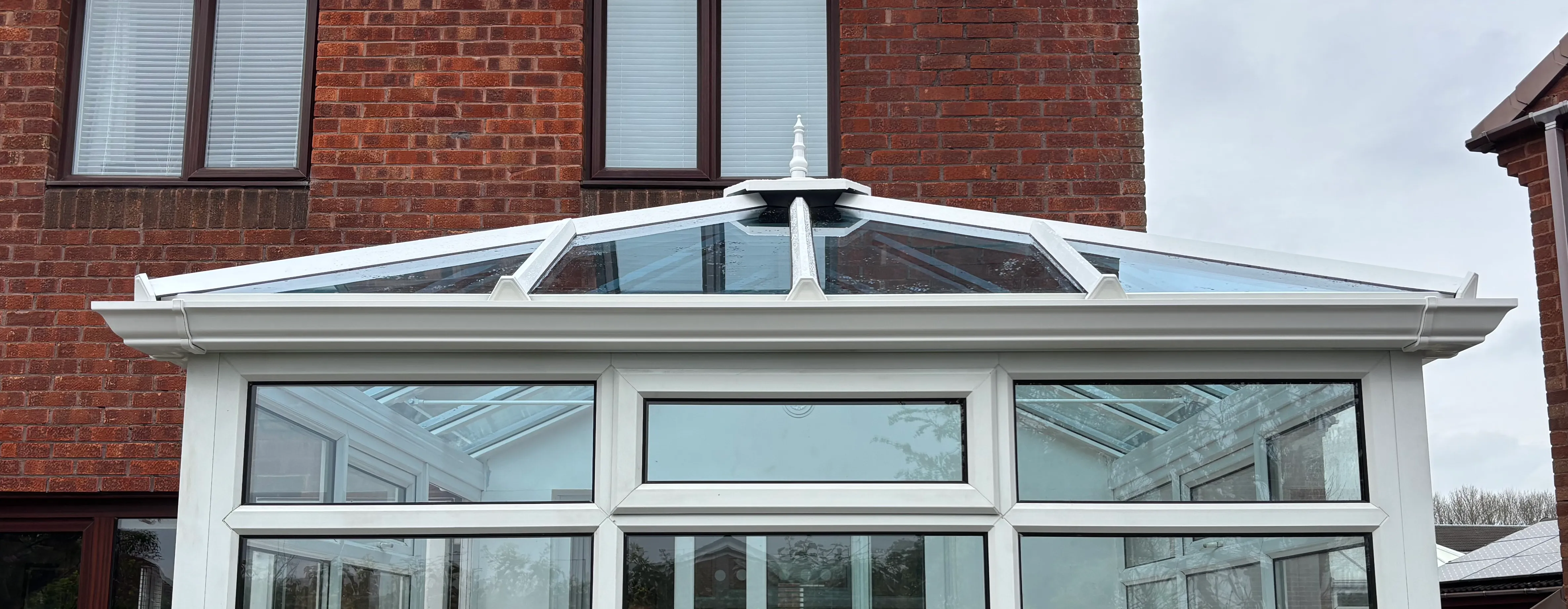 A completed blue-tinted glass conservatory roof in Usworth, Washington, on a white-framed conservatory against a brick house.